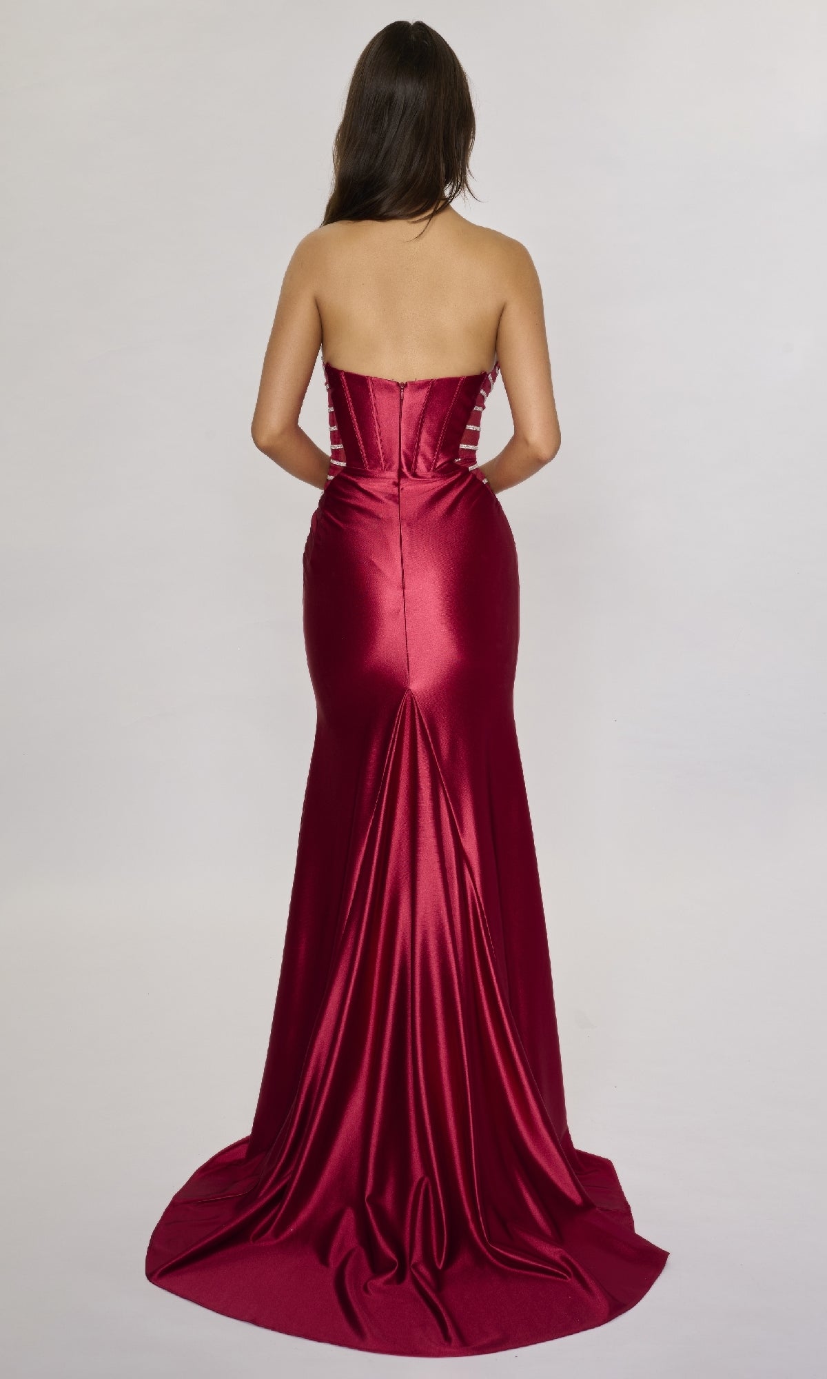 A woman wearing the Nina Canacci 5307, a strapless red satin formal dress with a fitted, floor-length silhouette, faces away from the camera against a plain light background.